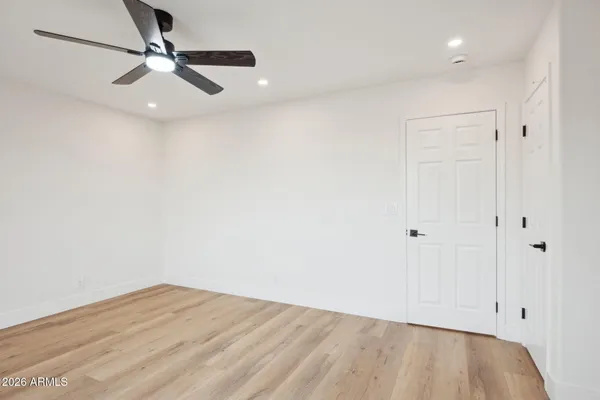 a view of empty room with wooden floor and fan