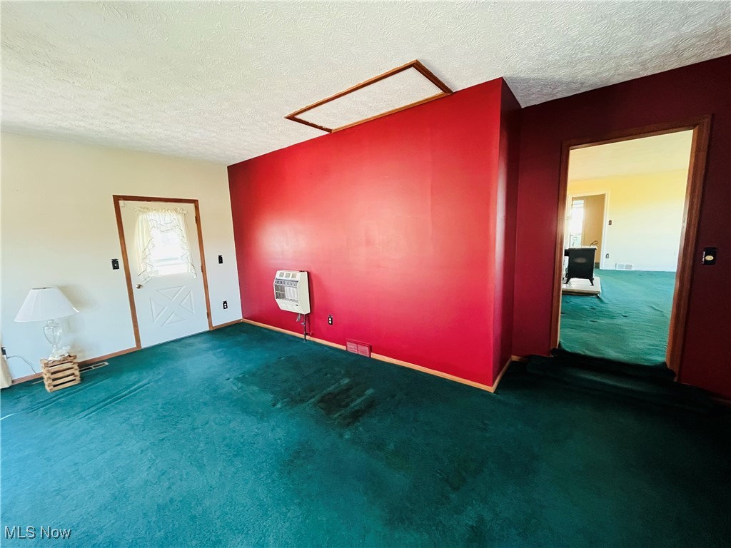 3210 Austinburg Road Ashtabula, OH 44004 - Photo 21 of 48 Unfurnished room with dark colored carpet, a textured ceiling, and heating unit