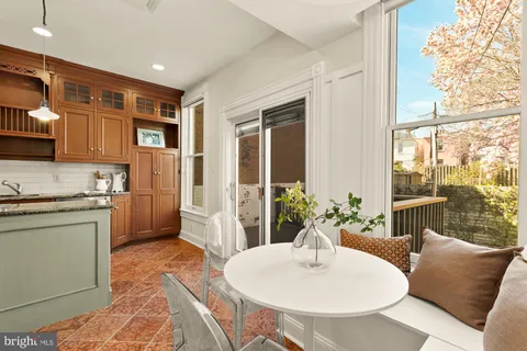 a living room with stainless steel appliances a dining table wooden floor and a large window