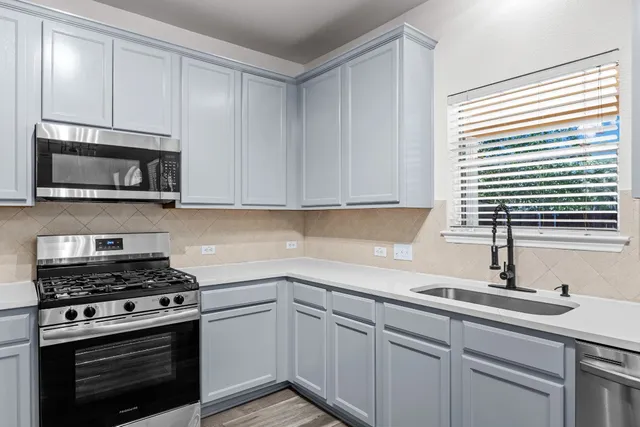 a kitchen with stainless steel appliances granite countertop a sink a stove and microwave