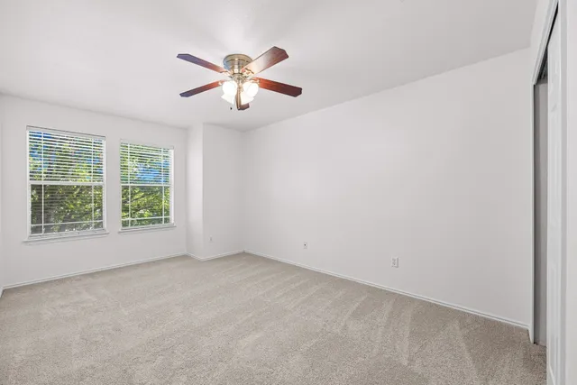an empty room with windows and fan