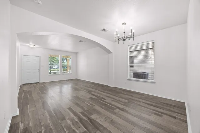 a view of an empty room with a window and wooden floor