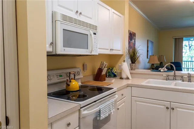 a kitchen with white cabinets and sink