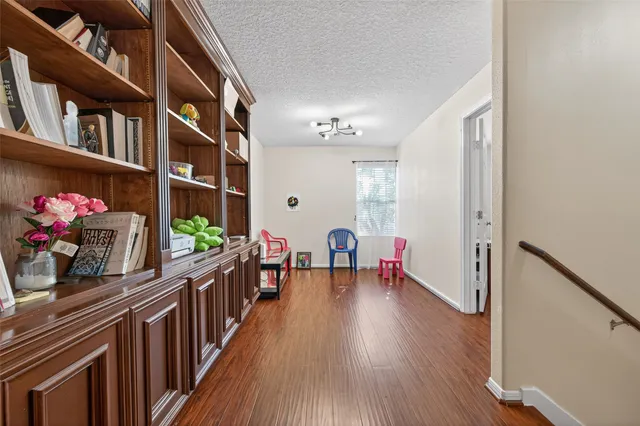 a hallway with a book shelf and wooden floor