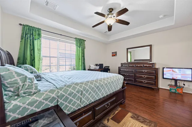 a bed sitting in a bedroom and dresser with wooden floor