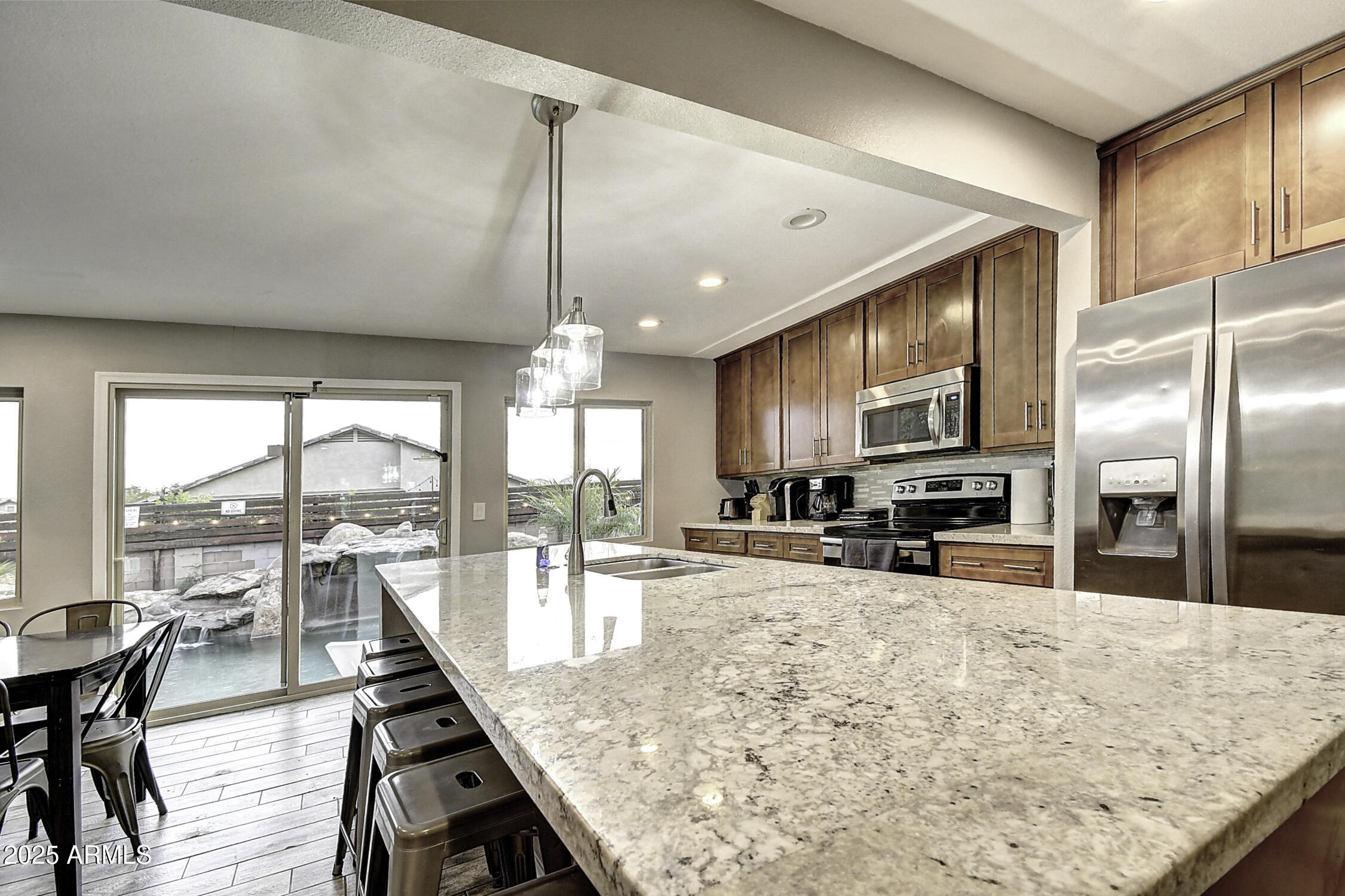 4101 East Nisbet Road Phoenix, AZ 85032 - Photo 31 of 64 a kitchen with stainless steel appliances kitchen island granite countertop a stove a refrigerator a sink a dining table and chairs with wooden floor