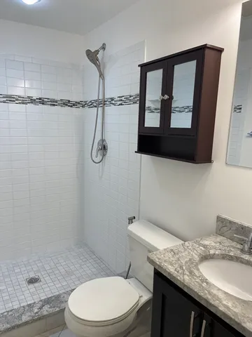 a bathroom with a granite countertop toilet sink and mirror