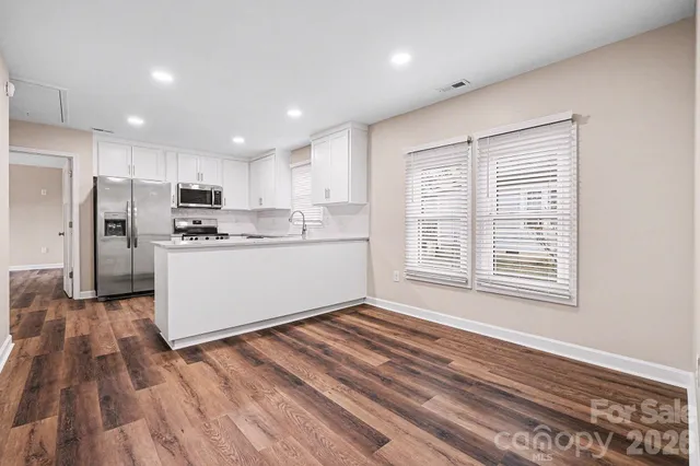 a kitchen with stainless steel appliances granite countertop a refrigerator a sink dishwasher a stove and white countertops with wooden floor