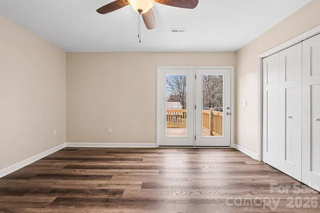 a view of empty room with wooden floor and fan