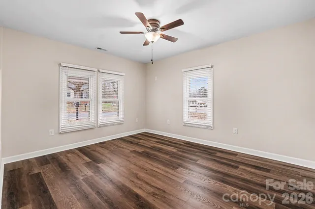 a view of an empty room with window and a chandelier fan