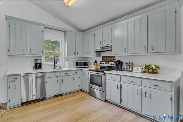 a kitchen with white cabinets white appliances sink and dishwasher with wooden floor
