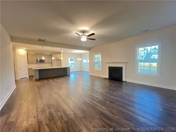 a view of an empty room with wooden floor and a fireplace
