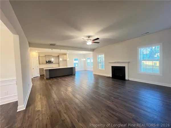 an empty room with wooden floor fireplace and windows