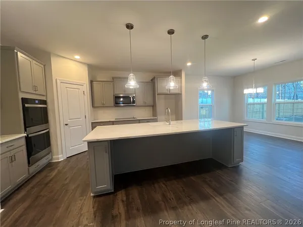 a large kitchen with kitchen island a counter space a sink stainless steel appliances and cabinets