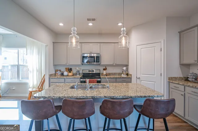 a kitchen with kitchen island granite countertop a stove a sink a dining table and chairs