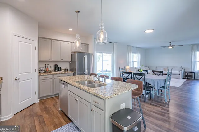 a kitchen with granite countertop kitchen island wooden floor center island and stainless steel appliances