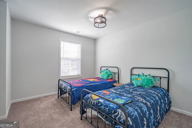 a bedroom with a large bed and a lamp on the dresser