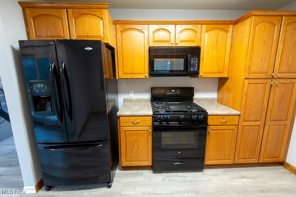 11819 Sheldon Road Mantua, OH 44255 - Photo 11 of 46 Kitchen featuring light luxury vinyl plank floors, plenty of cabinets and black appliances
