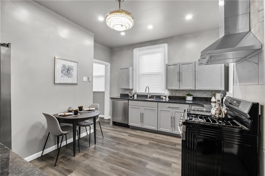 1256 Superior Avenue Pittsburgh, PA 15212 - Photo 28 of 50 a kitchen with stainless steel appliances granite countertop a stove top oven a sink dishwasher a dining table and chairs with wooden floor