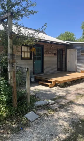 a view of a house with a small yard and large tree
