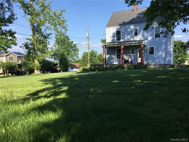 a view of a big house with a big yard and large trees