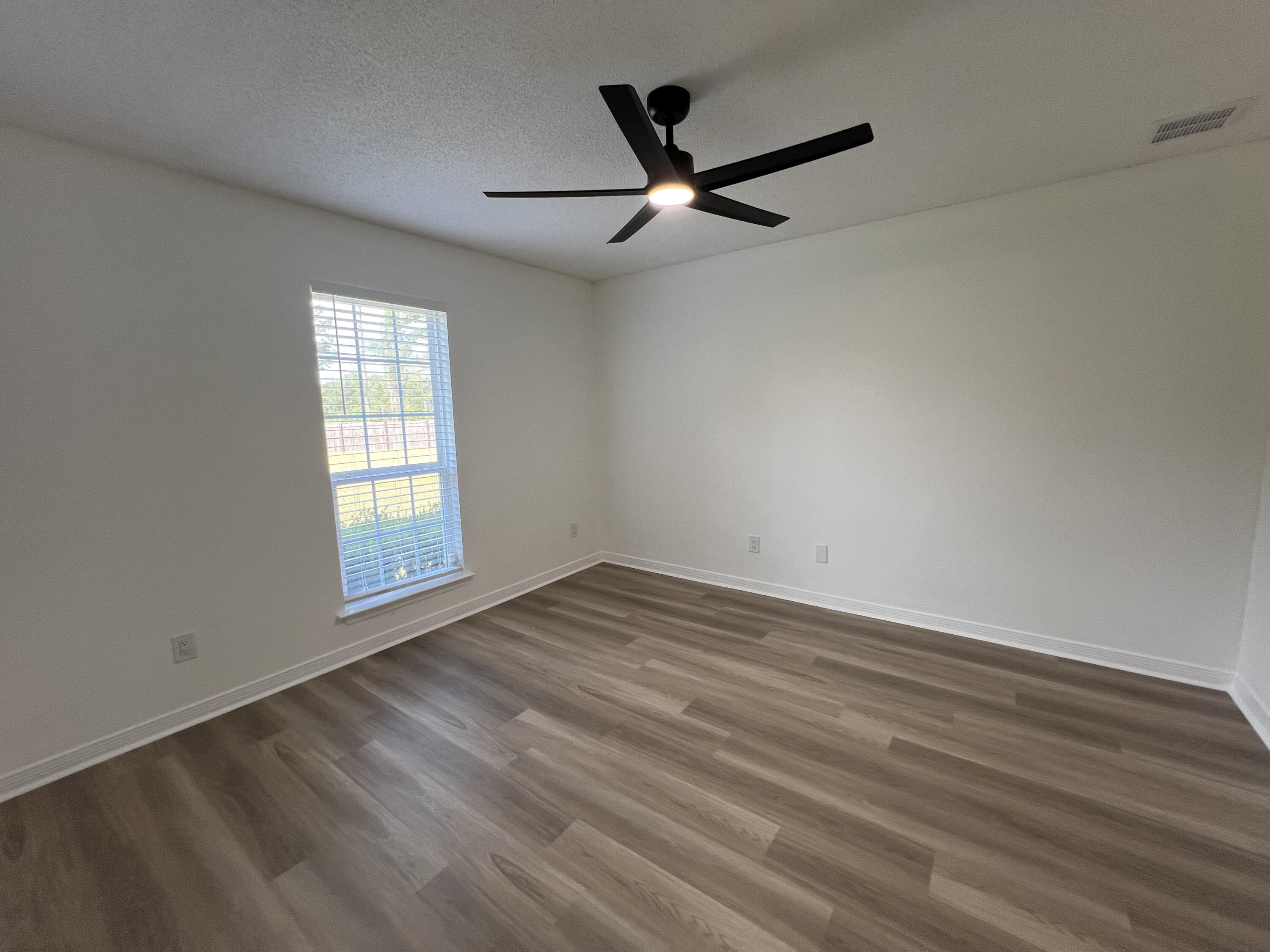 5330 John Lowery Road Jay, FL 32565 - Photo 12 of 30 an empty room with wooden floor fan and windows