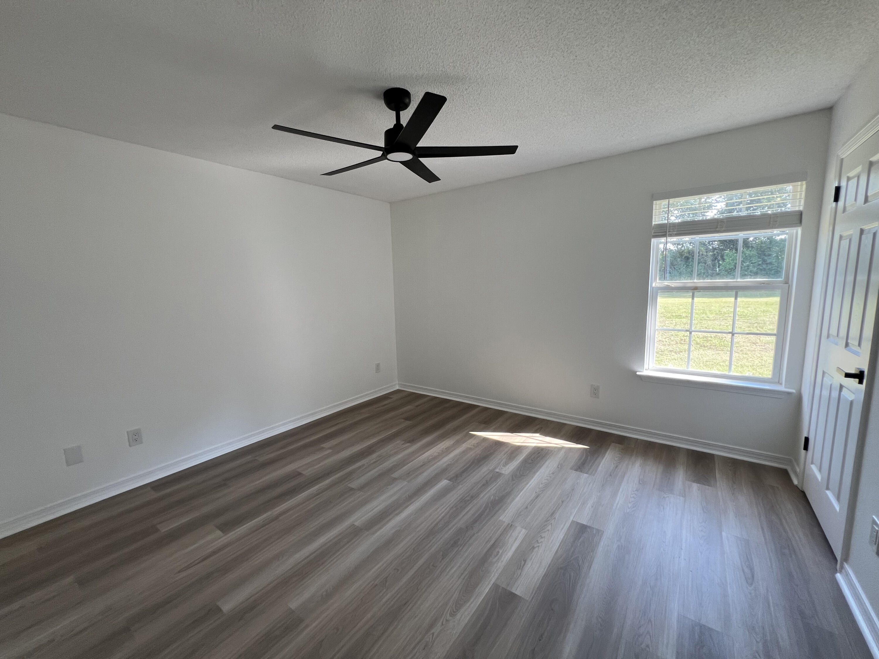 5330 John Lowery Road Jay, FL 32565 - Photo 3 of 30 an empty room with wooden floor fan and windows