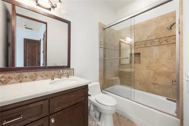 a bathroom with a granite countertop sink a toilet a mirror and shower