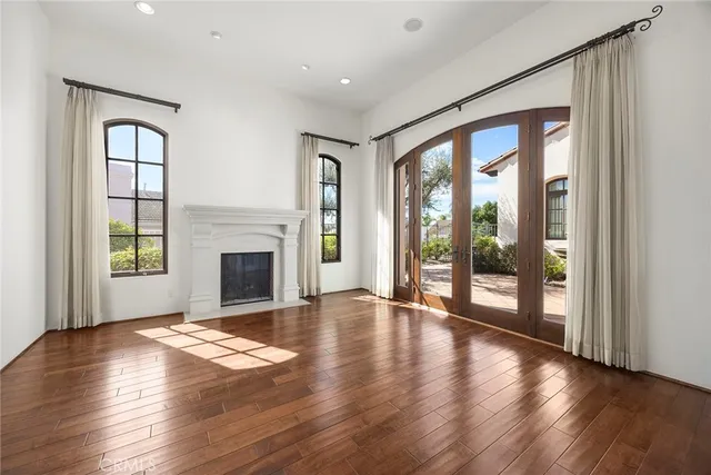 an empty room with windows fireplace and wooden floor