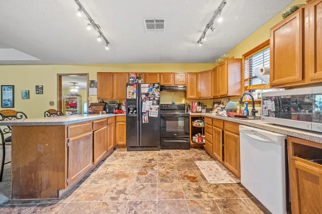 a large kitchen with stainless steel appliances kitchen island granite countertop a sink counter space cabinets and a large window