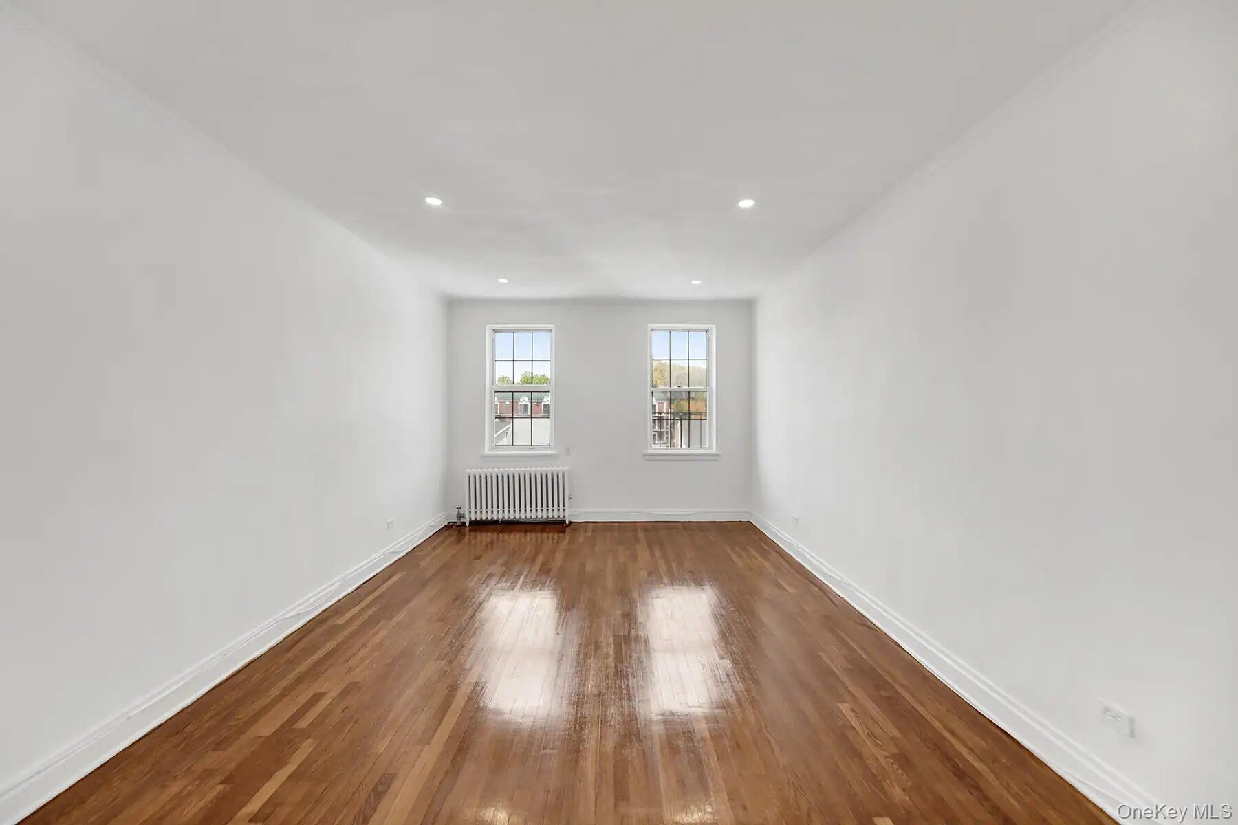 1 Ash Place, Unit 3A Great Neck, NY 11021 - Photo 6 of 10 Spacious room featuring hardwood flooring, white walls, two double-hung windows, recessed lighting, and a radiator