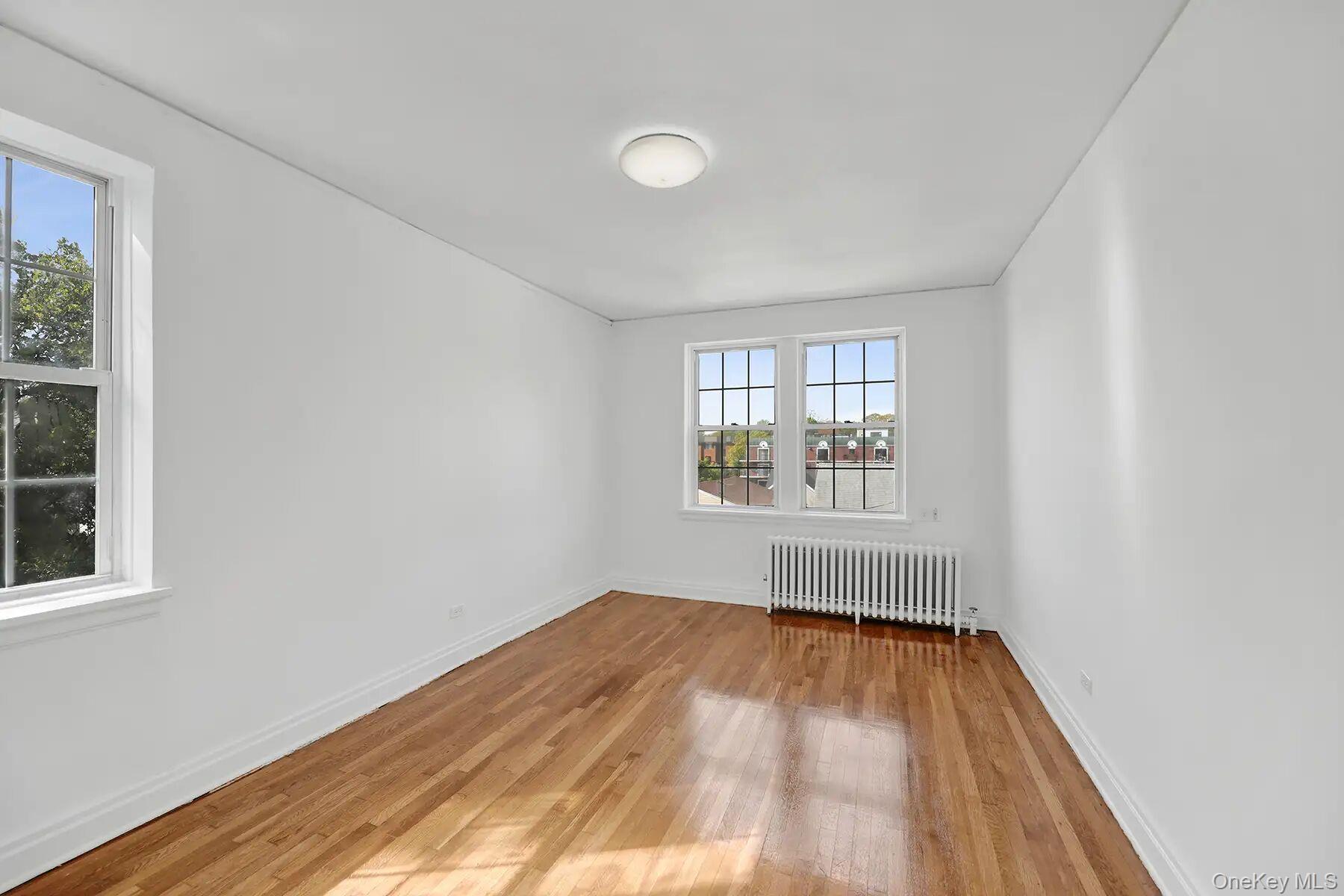 1 Ash Place, Unit 3A Great Neck, NY 11021 - Photo 8 of 10 Hardwood flooring throughout a bright room featuring white walls and trim