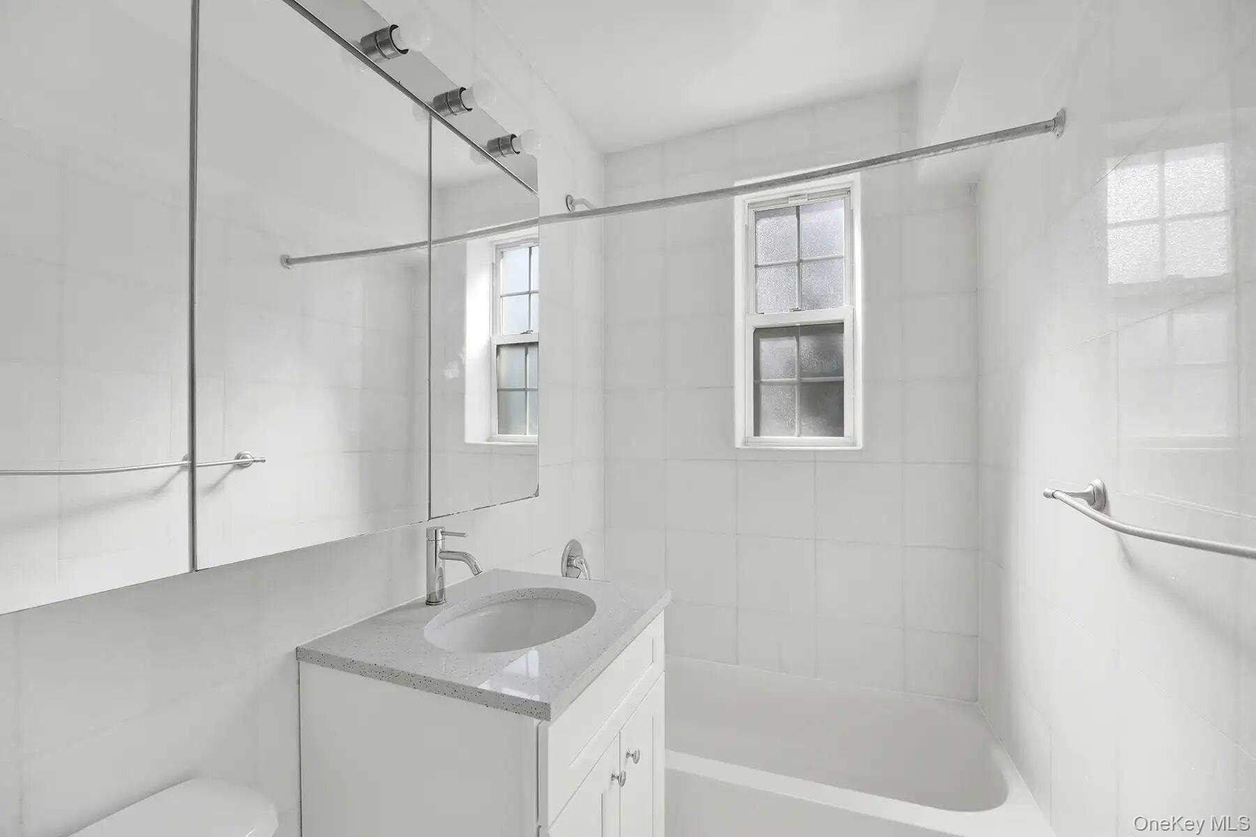 1 Ash Place, Unit 3A Great Neck, NY 11021 - Photo 10 of 10 Bathroom featuring a white vanity with a light-toned countertop, an integrated sink, and chrome fixtures