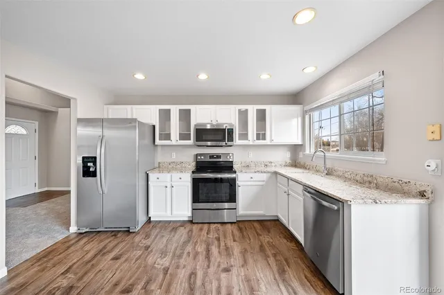 a kitchen with stainless steel appliances granite countertop a refrigerator a sink dishwasher a stove with wooden floors and cabinets