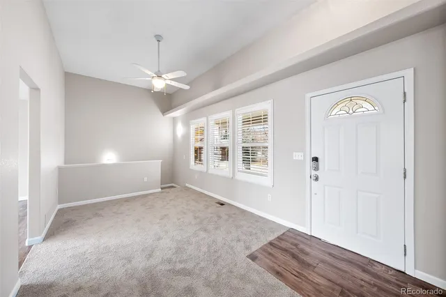 an empty room with chandelier fan and windows