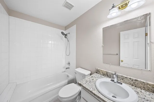 a bathroom with a granite countertop sink toilet and shower