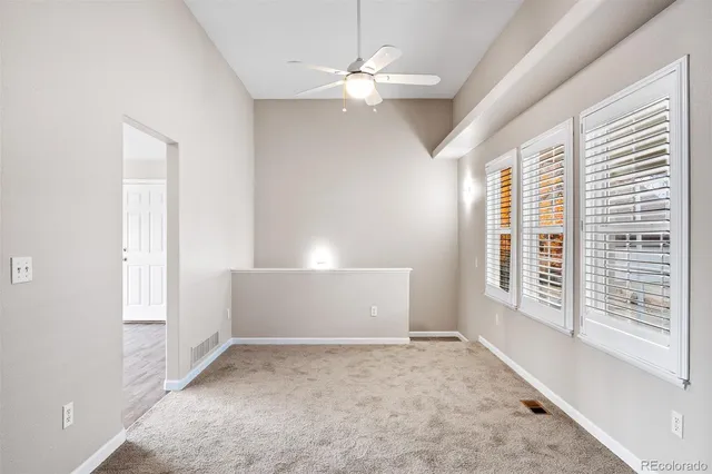 an empty room with windows and fan