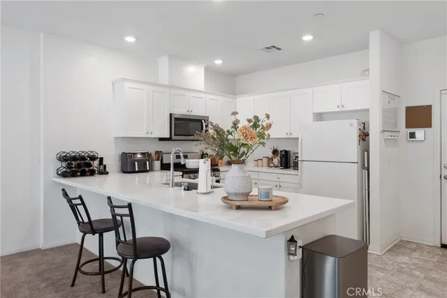a kitchen with refrigerator a sink and chairs