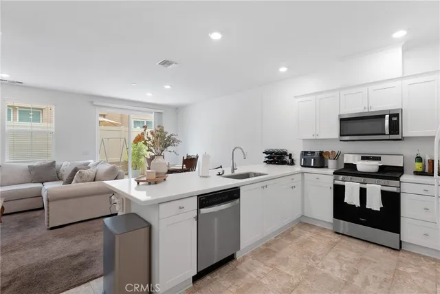 a large white open kitchen with a sink and dishwasher a stove top oven with wooden floor