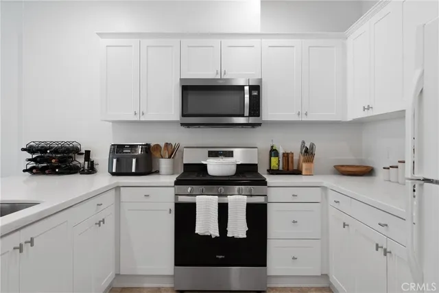 a kitchen with white cabinets and black appliances