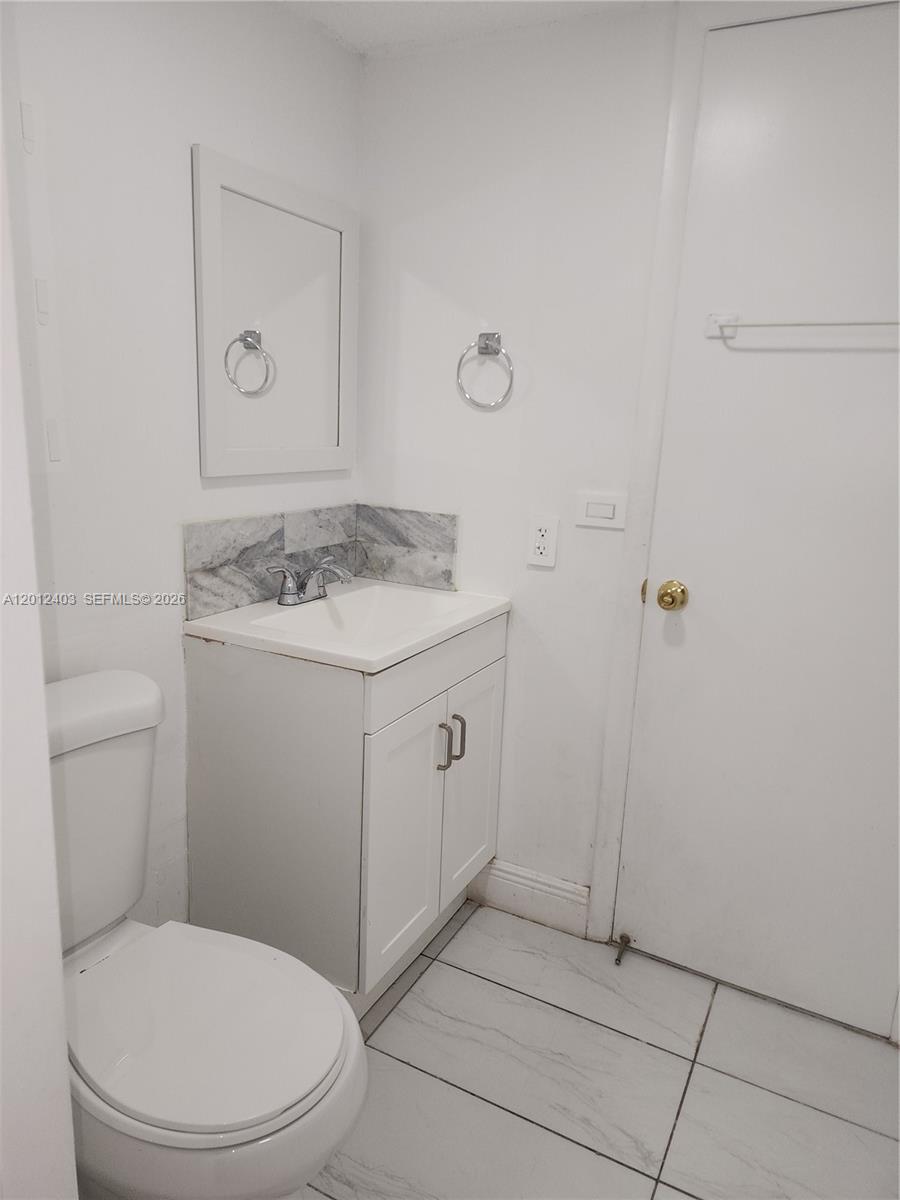 8990 Southwest 24th Street, Unit 19 Miami, FL 33165 - Photo 13 of 16 a bathroom with a granite countertop toilet sink and mirror
