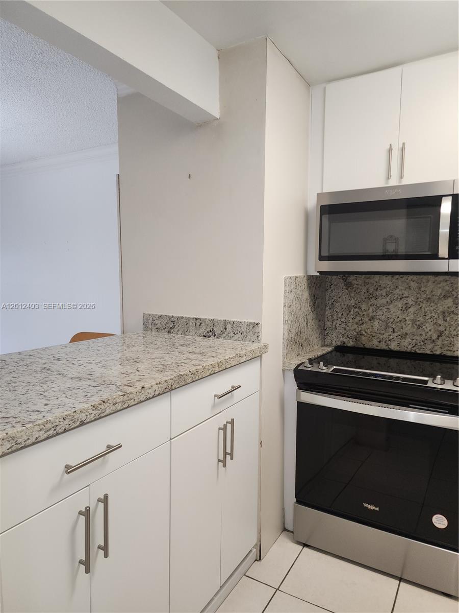 8990 Southwest 24th Street, Unit 19 Miami, FL 33165 - Photo 3 of 16 a kitchen with granite countertop white cabinets and stainless steel appliances