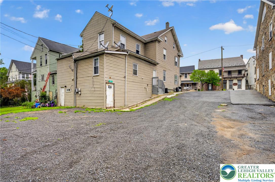 313 Main Street Slatington, PA 18080 - Photo 65 of 73 A well-maintained multi-level home stands prominently amidst a gravel lot, featuring traditional siding and a clear sky backdrop.