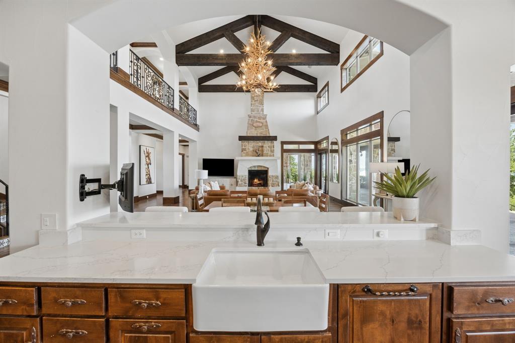 1180 McReynolds Road Sanger, TX 76266 - Photo 11 of 40 Kitchen counter featuring a large farmhouse sink with a dark-finish faucet, light-toned countertops, and rich wood cabinetry