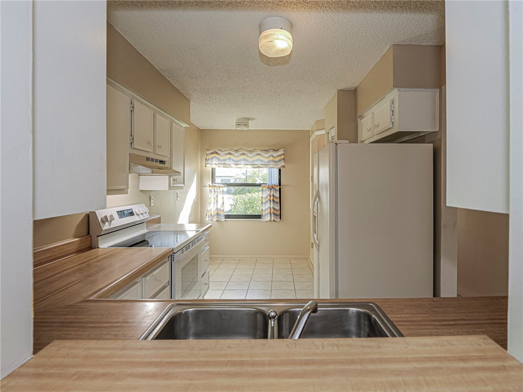 6006 Indrio Road, Unit B4 Fort Pierce, FL 34951 - Photo 6 of 36 a kitchen with stainless steel appliances kitchen island granite countertop a sink and white cabinets