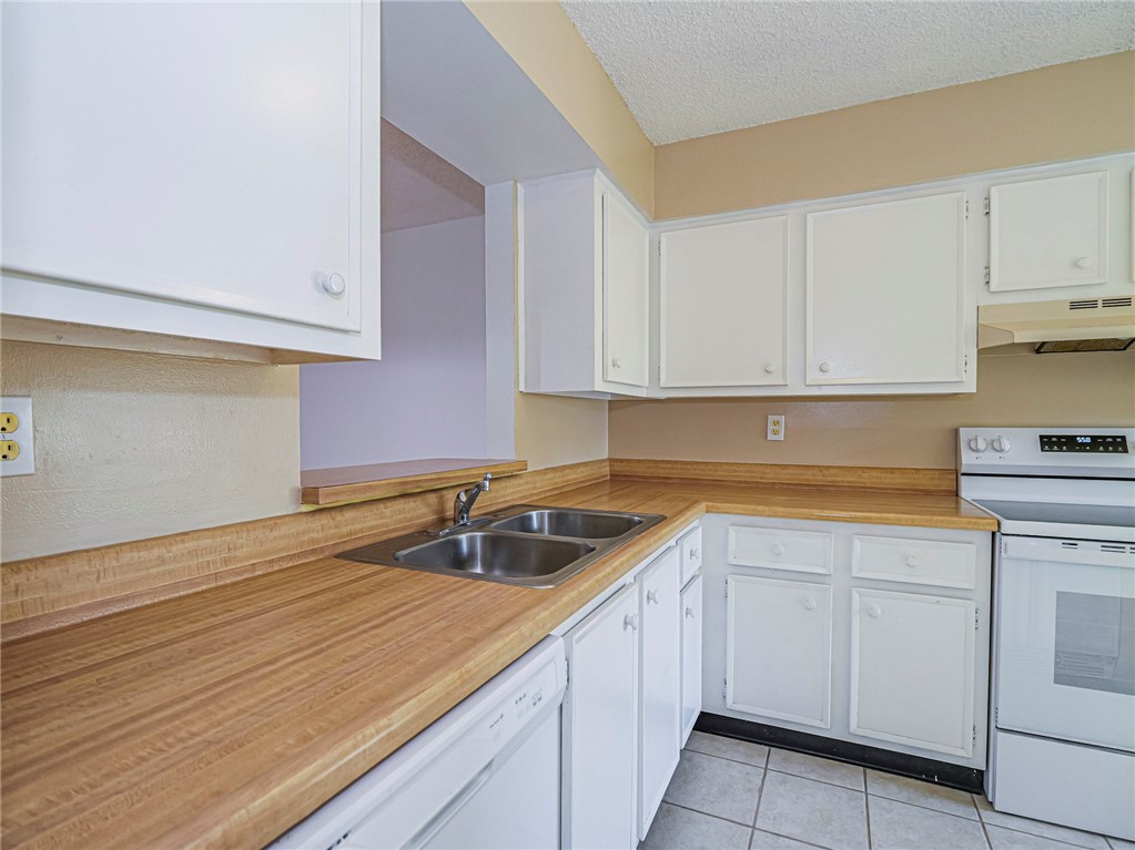 6006 Indrio Road, Unit B4 Fort Pierce, FL 34951 - Photo 7 of 36 a kitchen with white cabinets sink and dishwasher