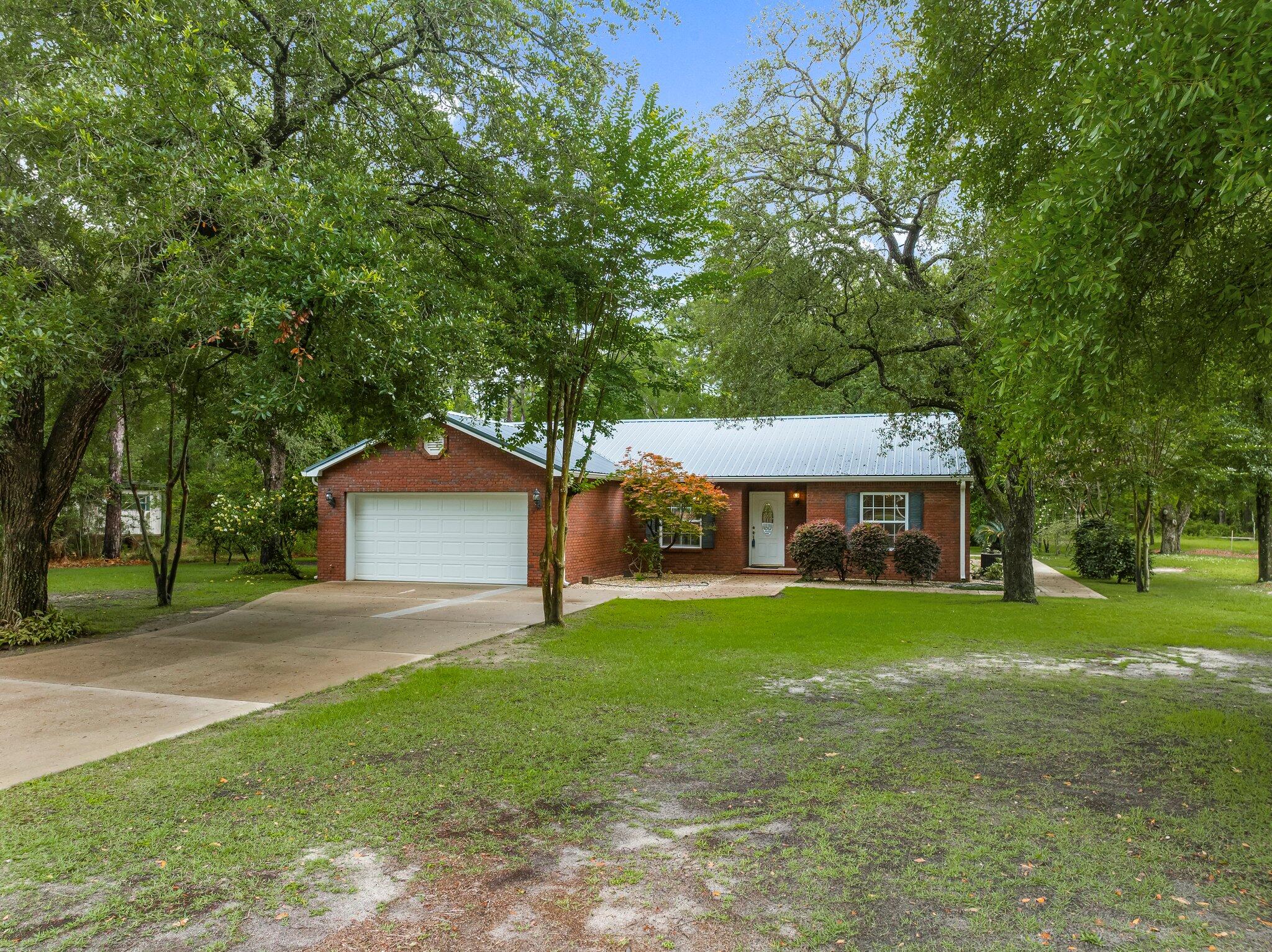 107 Rodney Drive Freeport, FL 32439 - Photo 3 of 34 a front view of a house with a garden and trees