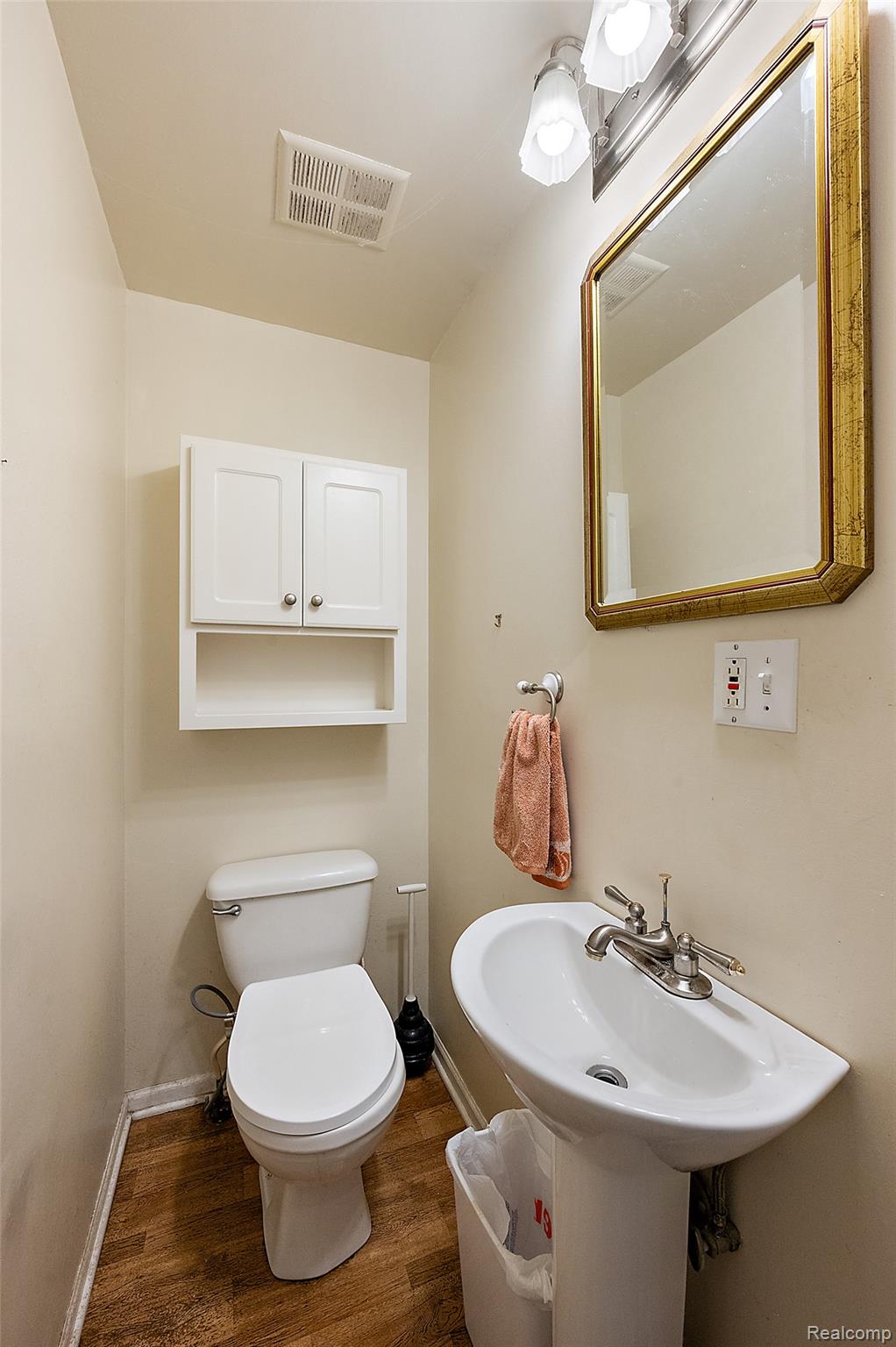 930 Little Hill Court Rochester, MI 48307 - Photo 29 of 38 Powder room featuring a pedestal sink, white toilet, and wood-finish flooring