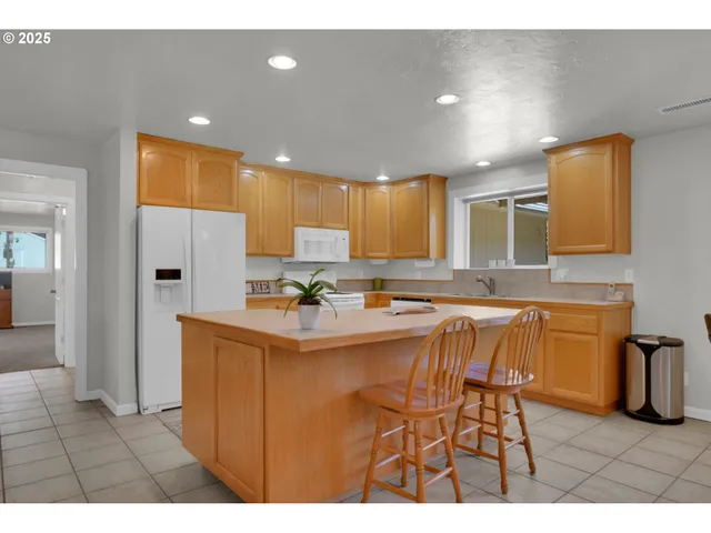 a large white kitchen with stainless steel appliances granite countertop a sink dishwasher a dining table and chair with wooden floor