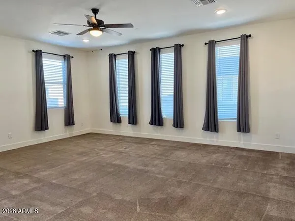 a view of an empty room with windows and ceiling fan